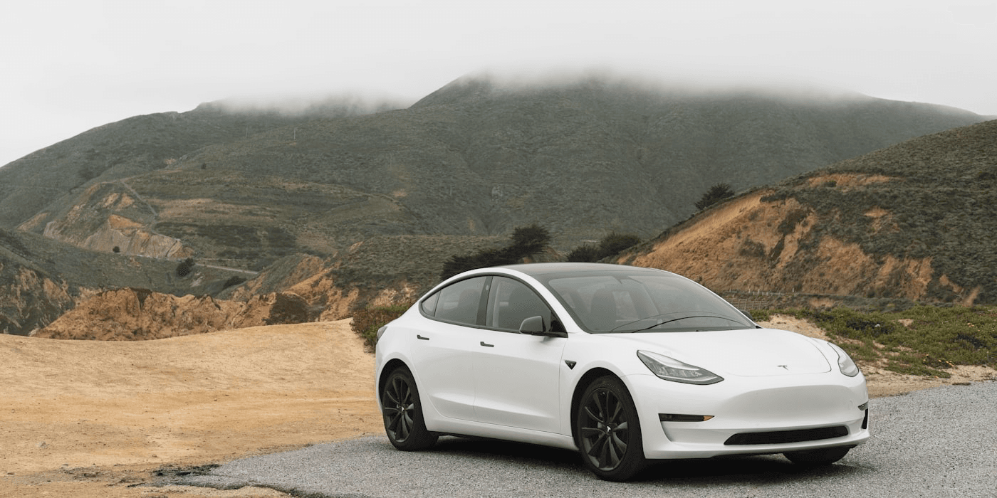 White electric car parked on a mountain road