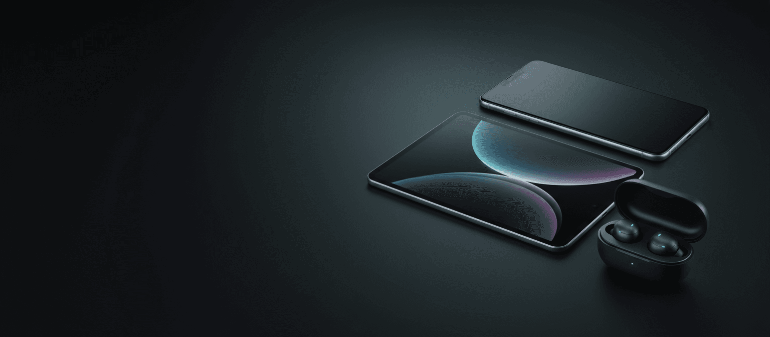 A smartphone, tablet and wireless earbuds on a dark surface
